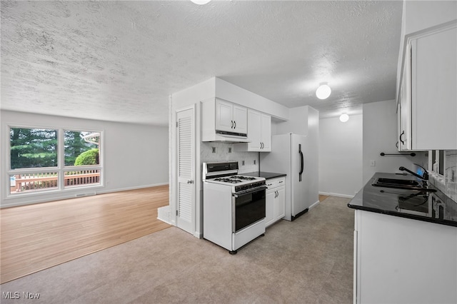 3612 Vezber Dr, Seven Hills, OH 44131 - kitchen with white gas stove, dark countertops, a textured ceiling, white cabinets, and light carpet