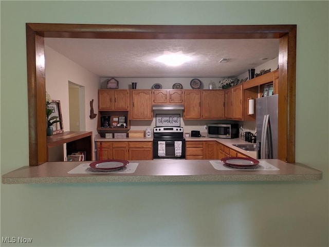 963 Ivydale Rd, Clay, WV 25043 - kitchen with appliances with stainless steel finishes, under cabinet range hood, a peninsula, and light countertops