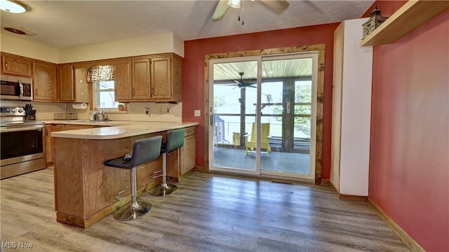 816 Vincent Dr, Loudonville, OH 44842 - kitchen with appliances with stainless steel finishes, a ceiling fan, light countertops, a peninsula, and light wood-style flooring