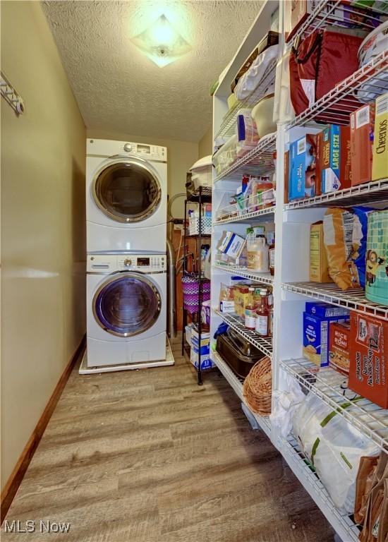 816 Vincent Dr, Loudonville, OH 44842 - washroom with stacked washer and clothes dryer, a textured ceiling, and wood finished floors