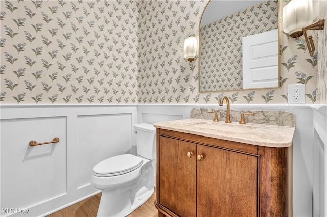 2705 Rocky Ridge Dr, Westlake, OH 44145 - half bathroom featuring wallpapered walls, vanity, a wainscoted wall, and wood finished floors