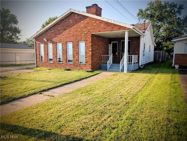 1305 14th St, Vienna, WV 26105 - view of front of house with brick siding, a chimney, and a front yard