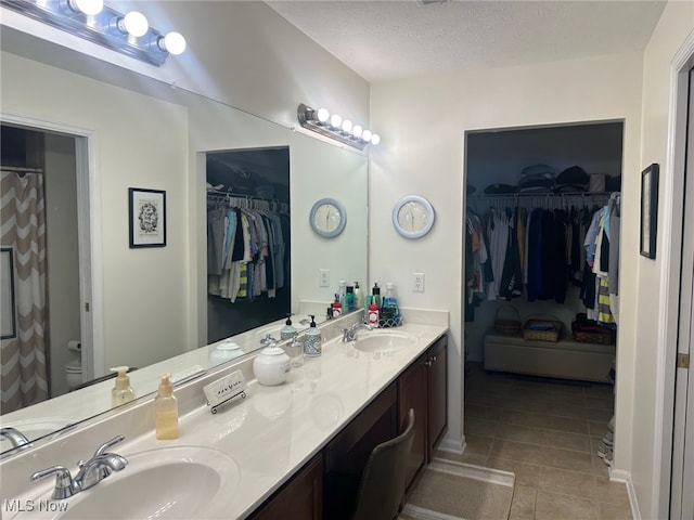 5-118 The Flds, Williamstown, WV 26187 - bathroom featuring double vanity, tile patterned flooring, a walk in closet, and a textured ceiling