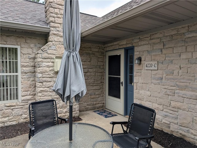 4220 Tannybrooke Ln NW Unit 13C, Canton, OH 44718 - view of exterior entry with roof with shingles, a patio, a chimney, and stone siding