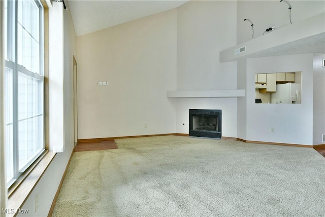 3406 Ivy Hill Cir Unit B, Cortland, OH 44410 - unfurnished living room with high vaulted ceiling, carpet flooring, plenty of natural light, and a fireplace with flush hearth