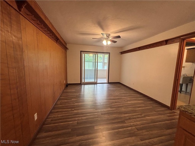 25320 Clubside Dr Unit 6, North Olmsted, OH 44070 - spare room featuring a ceiling fan, dark wood-type flooring, and wooden walls