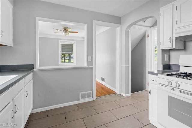19501 Libby Rd, Maple Heights, OH 44137 - kitchen with white gas range, arched walkways, white cabinets, and a ceiling fan