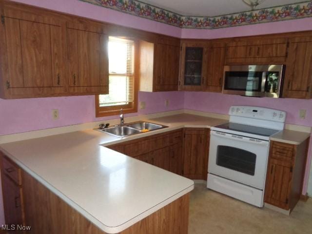 4326 Wood Thrush Dr, Parma, OH 44134 - kitchen with stainless steel microwave, white electric range oven, brown cabinets, a peninsula, and light countertops