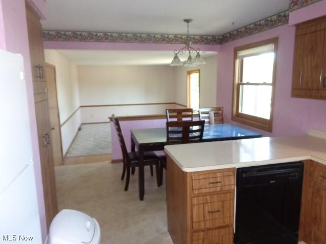4326 Wood Thrush Dr, Parma, OH 44134 - kitchen with black dishwasher, a peninsula, brown cabinets, light countertops, and hanging light fixtures