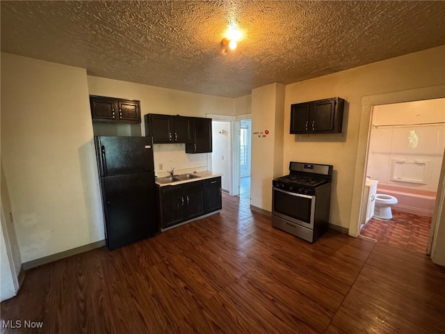1185 E 74th St, Cleveland, OH 44103 - kitchen featuring freestanding refrigerator, stainless steel gas stove, dark wood-style flooring, light countertops, and a textured ceiling
