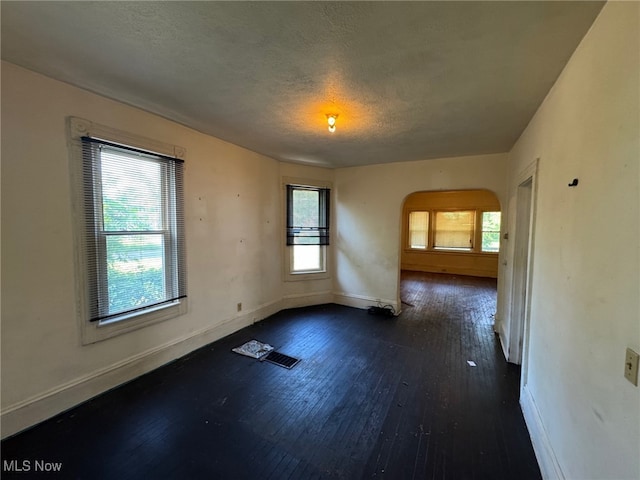 1185 E 74th St, Cleveland, OH 44103 - spare room featuring arched walkways, dark wood-type flooring, and a textured ceiling