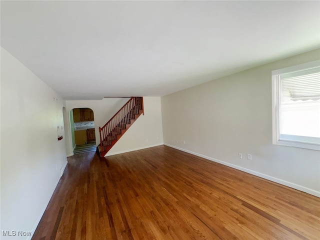 15920 Grove St, Middlefield, OH 44062 - unfurnished living room featuring arched walkways, wood finished floors, and stairs