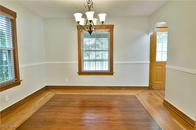 400 Spring St, Struthers, OH 44471 - empty room featuring wood finished floors, arched walkways, and a chandelier