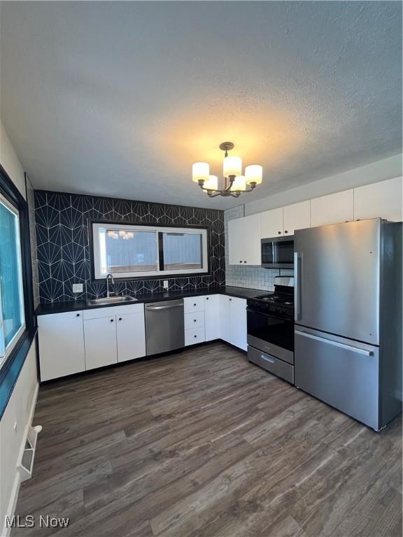 1405 E Cherokee Trl, Sandusky, OH 44870 - kitchen featuring appliances with stainless steel finishes, dark countertops, a chandelier, white cabinetry, and decorative backsplash