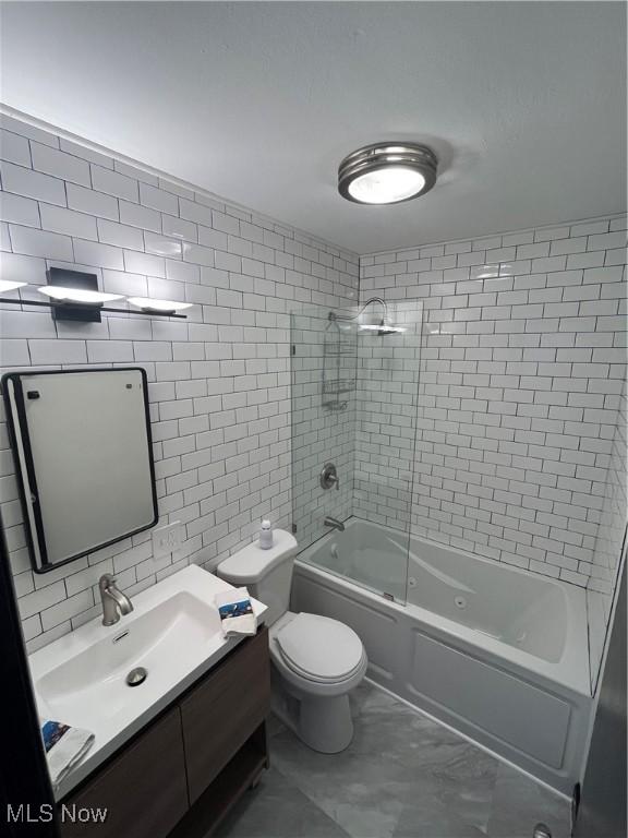 1405 E Cherokee Trl, Sandusky, OH 44870 - bathroom with tile walls, vanity, combined bath / shower with glass door, marble look tiles, and decorative backsplash