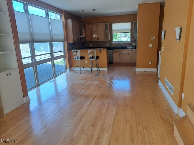 12595 Larchmere Blvd Unit E6, Cleveland, OH 44120 - kitchen with light wood-style flooring, a kitchen bar, backsplash, stainless steel dishwasher, and glass insert cabinets