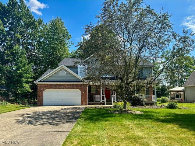 132 Beechwood Dr, Cortland, OH 44410 - view of front of house featuring driveway, an attached garage, a front lawn, covered porch, and brick siding