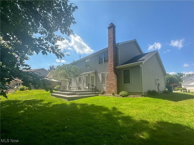 132 Beechwood Dr, Cortland, OH 44410 - back of property featuring a chimney, a lawn, and a wooden deck