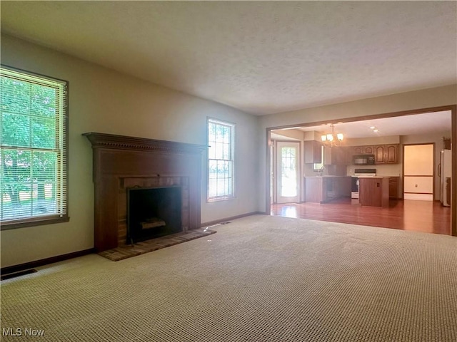 132 Beechwood Dr, Cortland, OH 44410 - unfurnished living room featuring a chandelier, a fireplace with raised hearth, and carpet floors