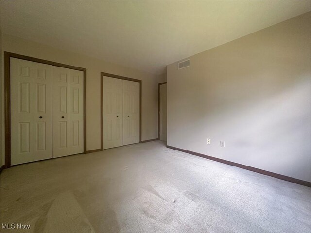 132 Beechwood Dr, Cortland, OH 44410 - unfurnished bedroom featuring light carpet and two closets