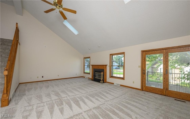 596 Glenmere Pl, Barberton, OH 44203 - unfurnished living room featuring a skylight, light carpet, ceiling fan, a fireplace with flush hearth, and high vaulted ceiling
