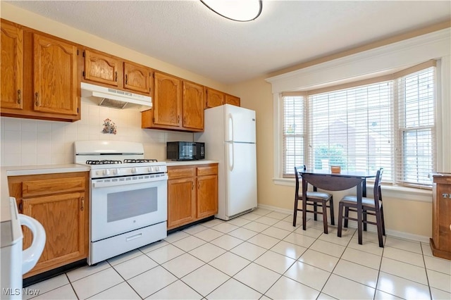 6706 Hogan Way NW, Canton, OH 44718 - kitchen with white appliances, under cabinet range hood, light countertops, and brown cabinets