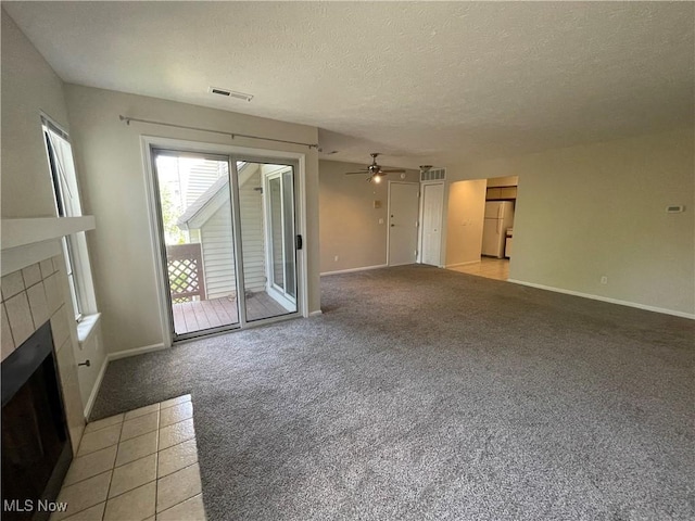 1304 Cedarwood Dr Unit D2, Westlake, OH 44145 - unfurnished living room featuring a tiled fireplace, light colored carpet, a ceiling fan, and a textured ceiling
