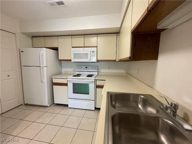 1304 Cedarwood Dr Unit D2, Westlake, OH 44145 - kitchen with white appliances, light countertops, light tile patterned floors, and cream cabinetry