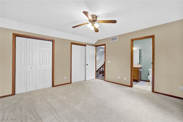 1550 Rebel St SW, Canton, OH 44706 - unfurnished bedroom featuring multiple closets, light carpet, ensuite bath, lofted ceiling, and a ceiling fan