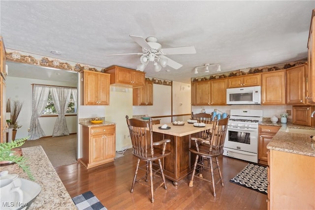 578 25th St NW, Massillon, OH 44647 - kitchen with white appliances, dark wood-style floors, ceiling fan, a center island, and a textured ceiling