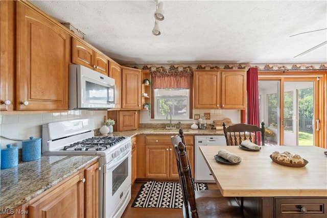 578 25th St NW, Massillon, OH 44647 - kitchen featuring white appliances, plenty of natural light, light stone countertops, a textured ceiling, and brown cabinetry