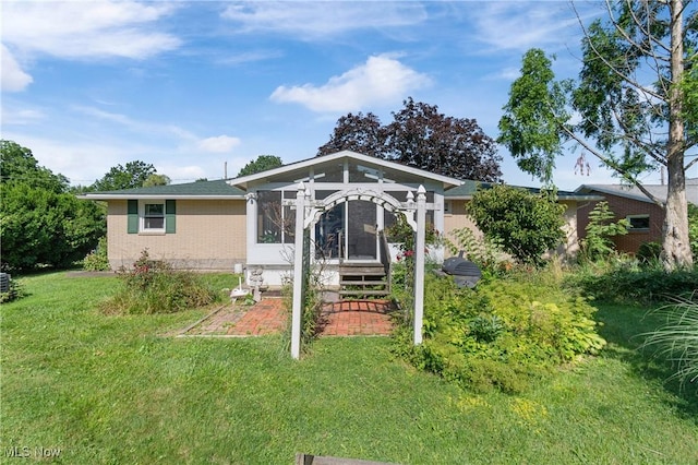 578 25th St NW, Massillon, OH 44647 - back of property featuring a lawn, brick siding, and a sunroom
