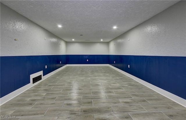 8171 Pheasant Ave NW, North Canton, OH 44720 - spare room with a textured wall, a textured ceiling, recessed lighting, and wood tiled floors