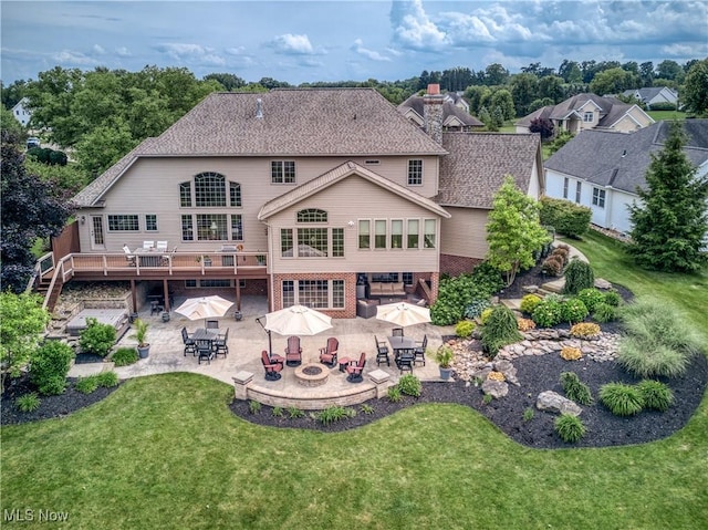 8309 Gentry St NW, Massillon, OH 44646 - rear view of property featuring outdoor dining area, an outdoor fire pit, a patio, a lawn, and a wooden deck