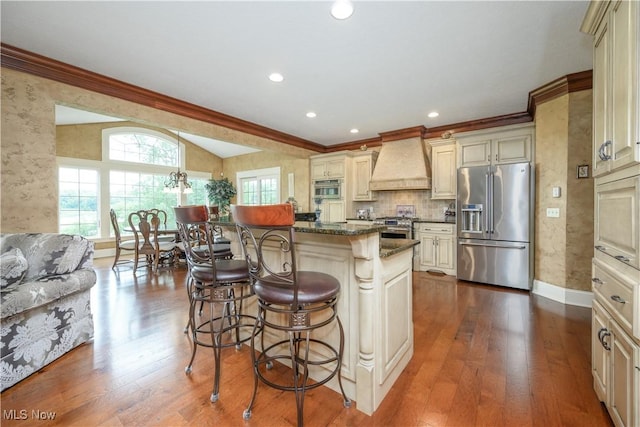8309 Gentry St NW, Massillon, OH 44646 - kitchen featuring stainless steel appliances, custom exhaust hood, ornamental molding, a kitchen bar, and cream cabinets