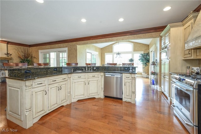 8309 Gentry St NW, Massillon, OH 44646 - kitchen featuring appliances with stainless steel finishes, light wood-type flooring, custom exhaust hood, healthy amount of natural light, and crown molding