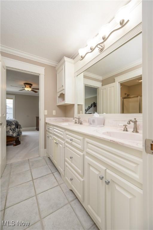 8309 Gentry St NW, Massillon, OH 44646 - ensuite bathroom with double vanity, tile patterned floors, ornamental molding, ceiling fan, and a shower with shower door