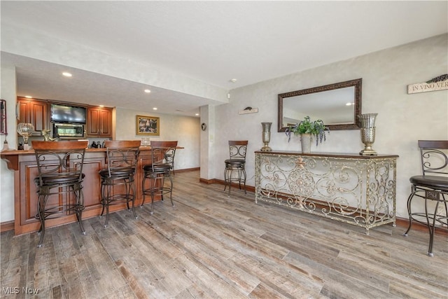 8309 Gentry St NW, Massillon, OH 44646 - kitchen with stainless steel microwave, wood finished floors, a breakfast bar area, recessed lighting, and a peninsula