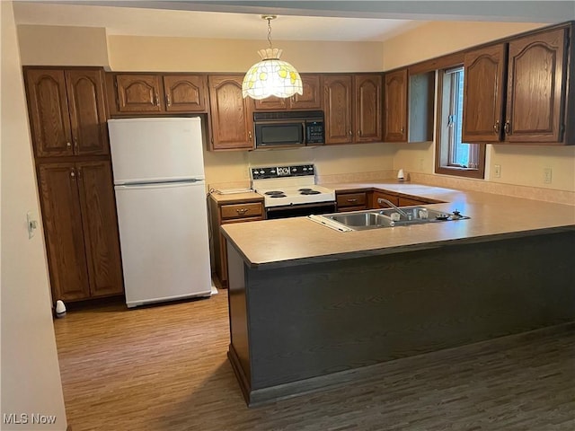 5450 King Graves Rd, Vienna, OH 44473 - kitchen featuring white appliances, wood finished floors, a peninsula, decorative light fixtures, and a chandelier