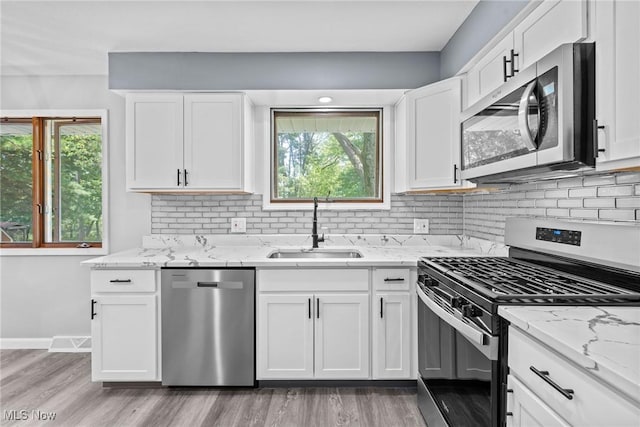 1303 E Dartmoor Ave, Seven Hills, OH 44131 - kitchen featuring appliances with stainless steel finishes, light stone counters, light wood-style floors, white cabinetry, and decorative backsplash