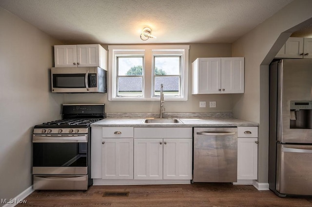 1320 21st St, Vienna, WV 26105 - kitchen featuring appliances with stainless steel finishes, white cabinets, dark wood-style flooring, light countertops, and a textured ceiling