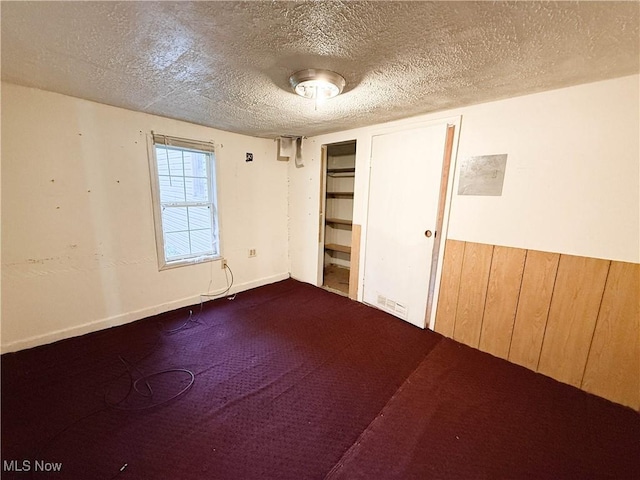 8756 Cook Rd, Salem, OH 44460 - unfurnished bedroom with a textured ceiling, wooden walls, and dark colored carpet
