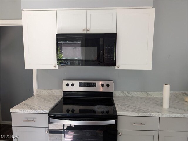 1146 Easton Dr, Akron, OH 44310 - kitchen featuring electric range, black microwave, light stone counters, and white cabinetry