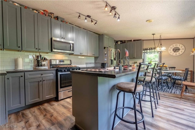 2176 Pageant Rd SE, Carrollton, OH 44615 - kitchen featuring stainless steel appliances, dark countertops, wood finished floors, a textured ceiling, and a breakfast bar