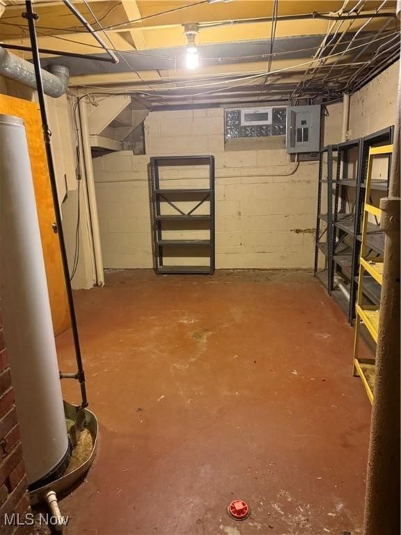 unfinished below grade area featuring electric panel and water heater