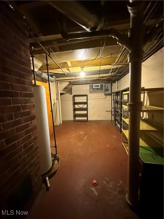 unfinished basement featuring electric panel and water heater