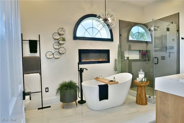 257 Country Club Dr SE, Warren, OH 44484 - full bath featuring a shower stall, a freestanding tub, a chandelier, marble finish flooring, and a glass covered fireplace