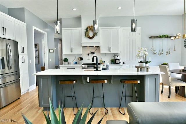 257 Country Club Dr SE, Warren, OH 44484 - kitchen with stainless steel refrigerator with ice dispenser, white cabinets, light wood finished floors, a breakfast bar, and recessed lighting