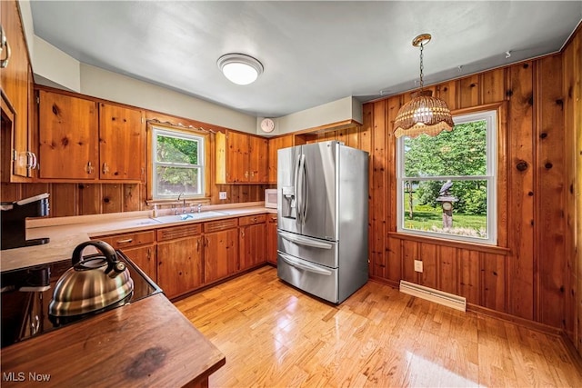 3988 Lake Rd, Conneaut, OH 44030 - kitchen with stainless steel refrigerator with ice dispenser, brown cabinets, wood walls, light countertops, and light wood-style floors