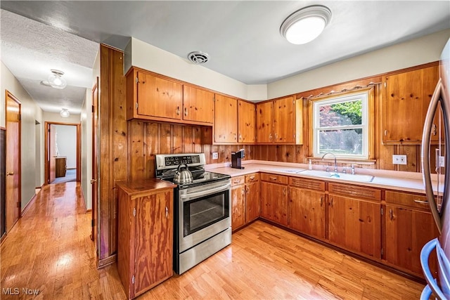 3988 Lake Rd, Conneaut, OH 44030 - kitchen with stainless steel appliances, brown cabinetry, and light wood-style floors